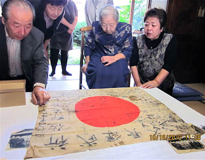 68年ぶりに帰ってきた夫の日章旗に見入る佐野あさ子さん（中央）